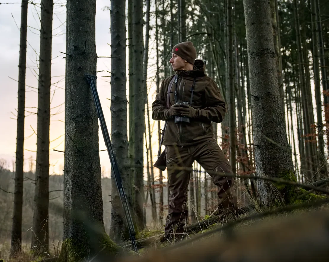 Jägare i skog iförd Härkila Aspire HWS Jacket i färgen Hunting Green