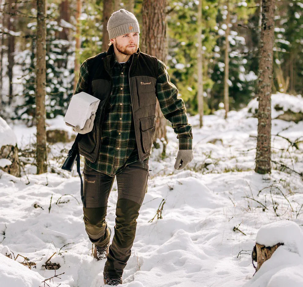 Jägare bär Pinewood Abisko Vest Suede väst under vinterjakt i skogsmiljö