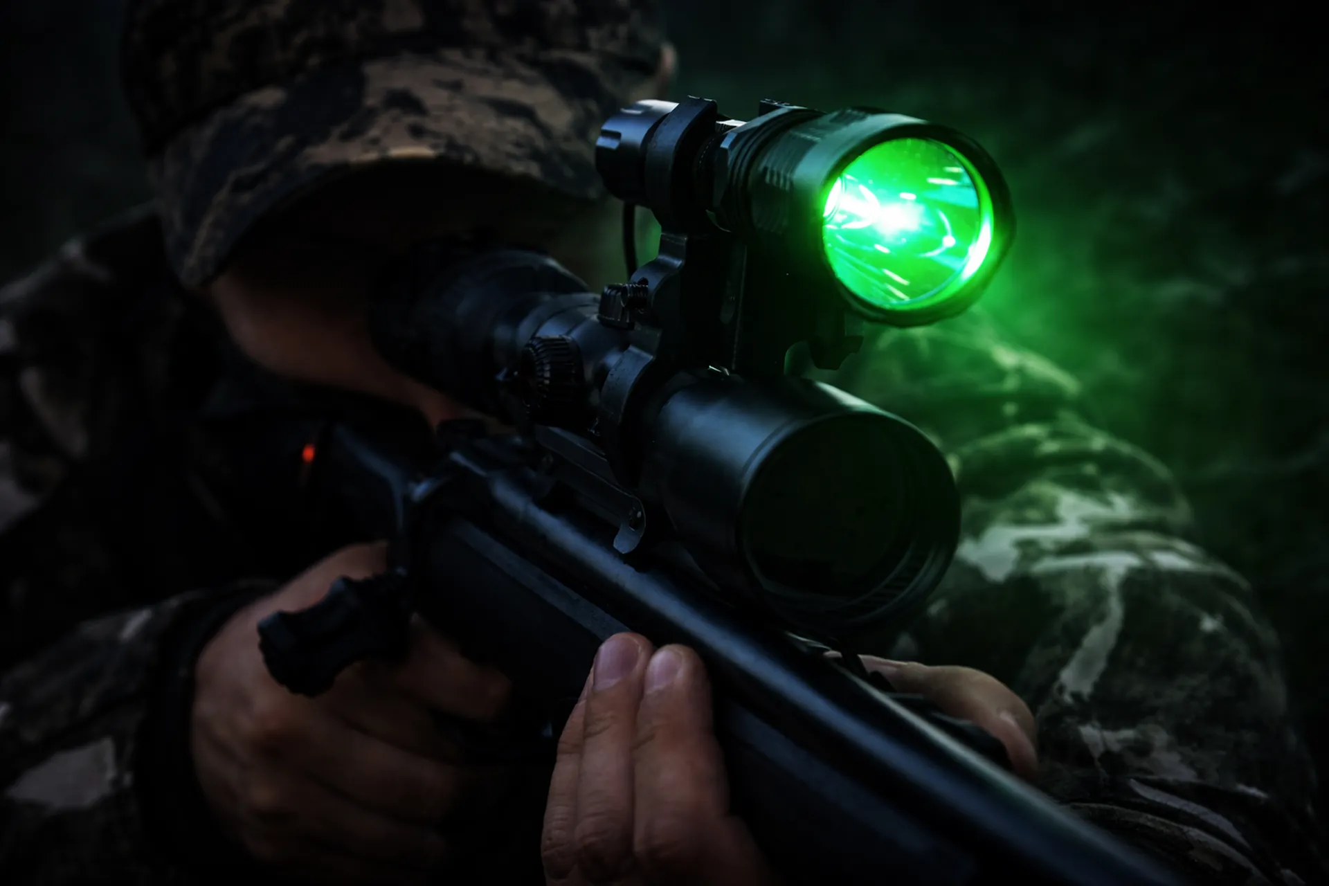Grön LED-ficklampa monterad ovanpå kikarsikte vid vildsvinsjakt i mörker, diskret grönt ljus för jakt och observation.