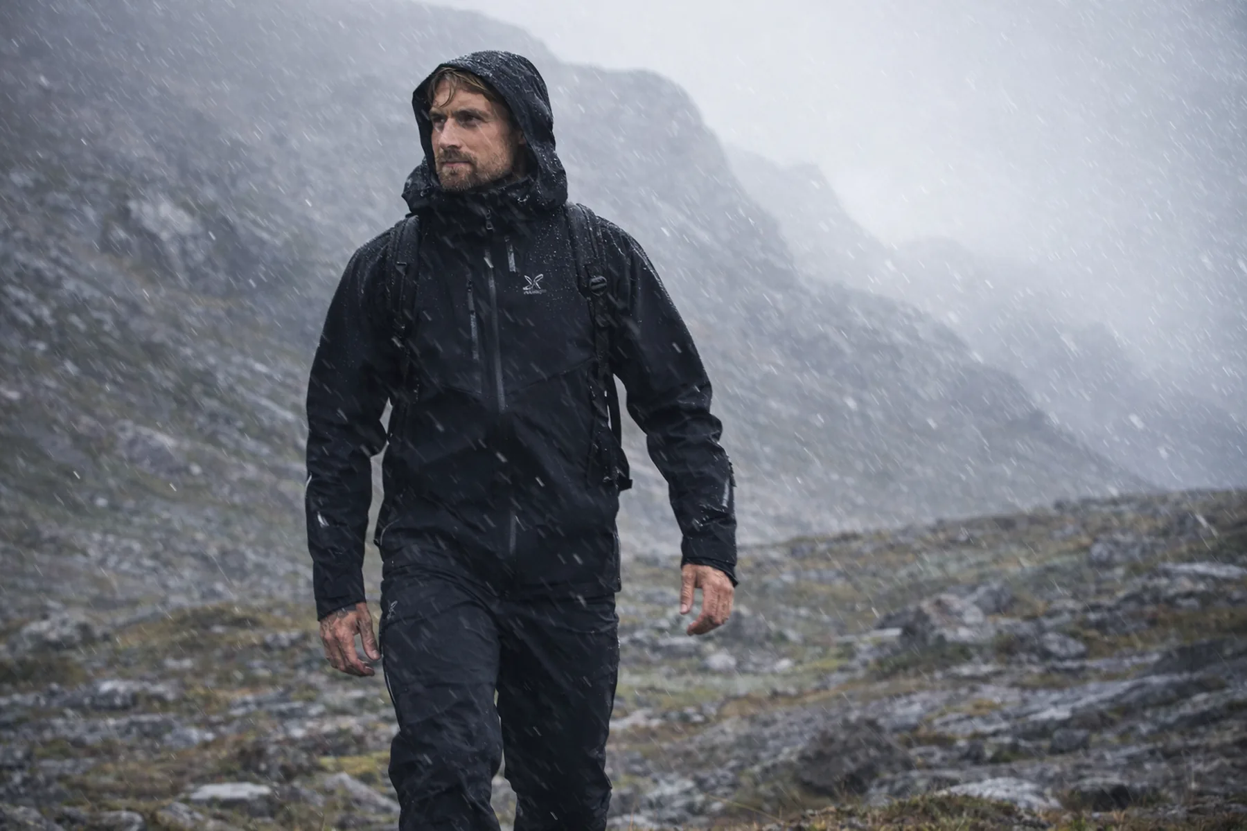 Vandrare i RevolutionRace Cyclone 3L skaljacka i blåsigt och regnigt fjällandskap